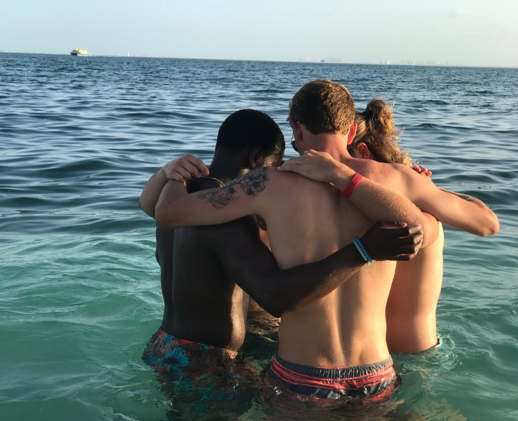 A group of men participating in a joyful event, hugging and immersing themselves in the refreshing ocean water.