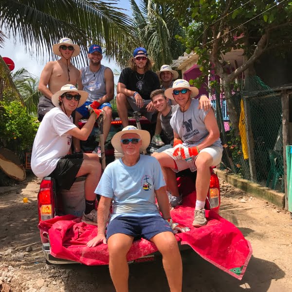 A group of people sitting in the back of a red truck.