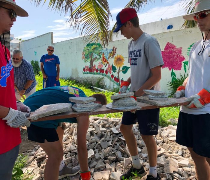 A group of people on a mission trip in Mexico, carrying a piece of wood.