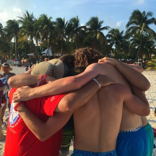 A group of people hugging on the beach.