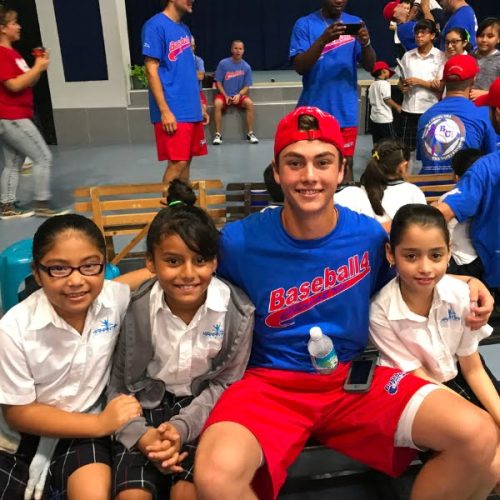 A group of kids posing for a photo with a baseball player.