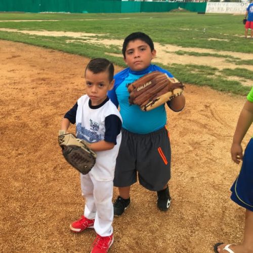 Two boys standing on a baseball field.